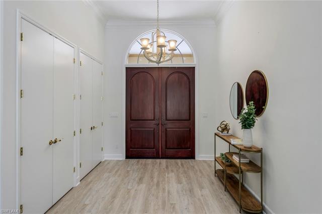 Entryway featuring ornamental molding, light wood-style floors, baseboards, and a notable chandelier