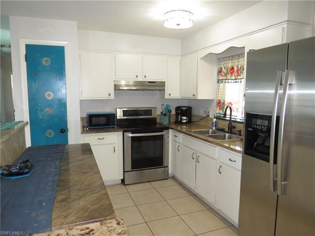 Kitchen with appliances with stainless steel finishes, a sink, white cabinets, and under cabinet range hood