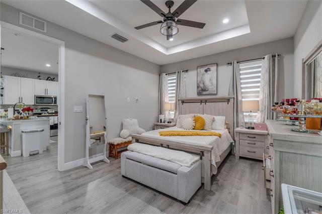 Bedroom featuring ceiling fan, a raised ceiling, and light wood-type flooring