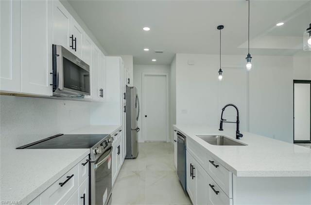 Kitchen with a sink, recessed lighting, stainless steel appliances, white cabinetry, and a kitchen island with sink