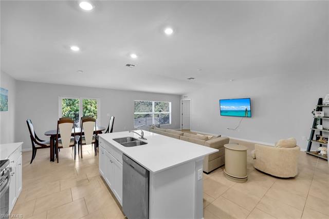 Kitchen featuring a sink, stainless steel appliances, light countertops, white cabinetry, and open floor plan