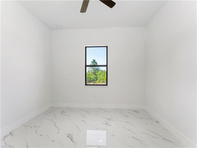 Unfurnished room featuring marble finish floor, baseboards, and ceiling fan