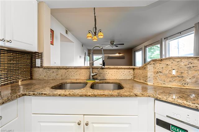 Kitchen with a sink, light stone counters, tasteful backsplash, and a wealth of natural light