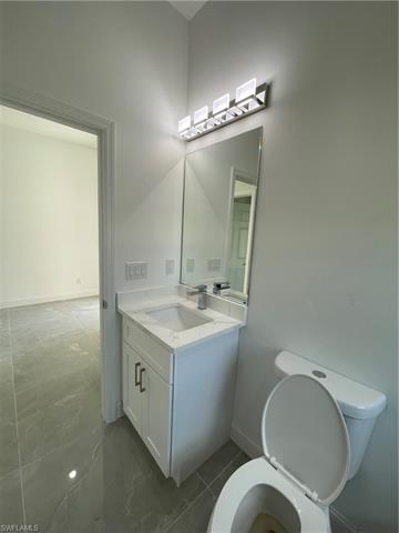 Half bathroom featuring vanity, toilet, and baseboards