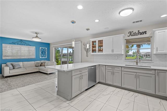 Kitchen featuring visible vents, marble finish floor, gray cabinetry, a sink, and dishwasher