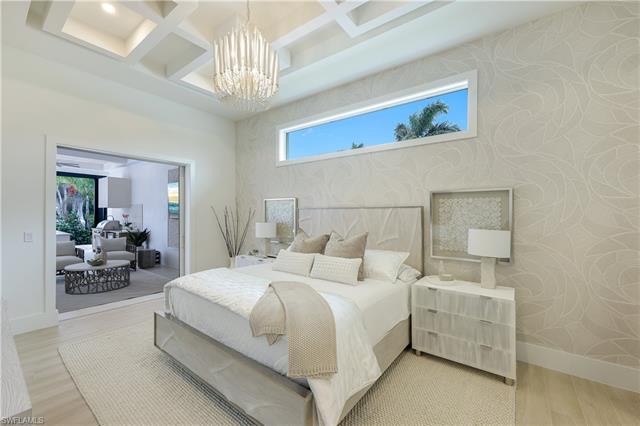 Bedroom featuring wallpapered walls, an inviting chandelier, light wood-style floors, and baseboards