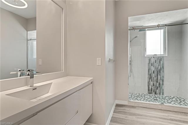 Full bath featuring wood finished floors, vanity, baseboards, and a shower stall