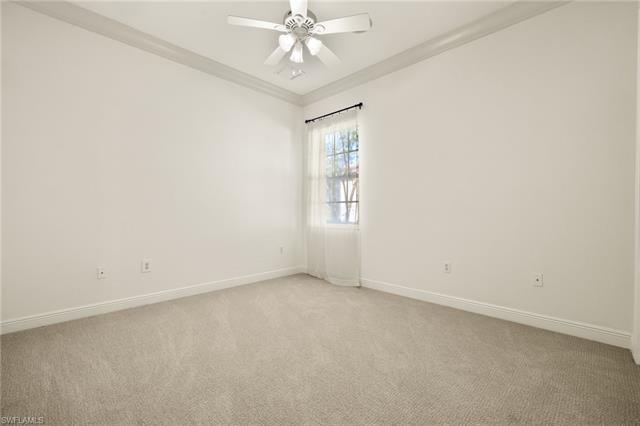 Spare room featuring light colored carpet, crown molding, baseboards, and ceiling fan