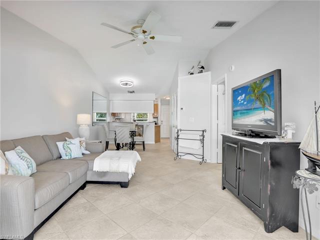 Living room with light tile patterned floors, visible vents, ceiling fan, and lofted ceiling