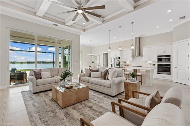 Living room with visible vents, beamed ceiling, light tile patterned floors, ceiling fan with notable chandelier, and a towering ceiling