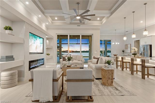 Living room featuring a premium fireplace, beam ceiling, a high ceiling, and ceiling fan with notable chandelier