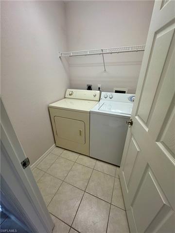 Clothes washing area featuring washer and clothes dryer, laundry area, and light tile patterned floors