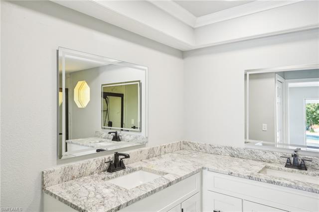 Bathroom with a sink, ornamental molding, and double vanity