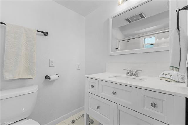 Full bathroom featuring vanity, a shower with shower door, baseboards, visible vents, and toilet