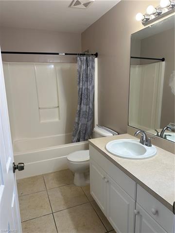 Full bathroom with tile patterned flooring, vanity, shower / tub combo with curtain, and toilet