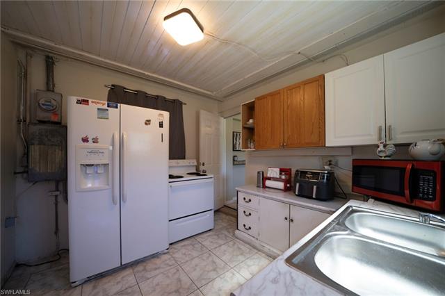 Kitchen with wood ceiling, light countertops, white cabinets, white appliances, and a sink