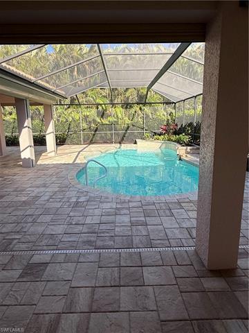 Outdoor pool featuring glass enclosure and a patio