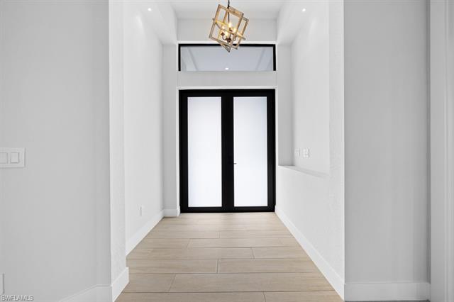 Hall featuring wood finish floors, baseboards, and an inviting chandelier