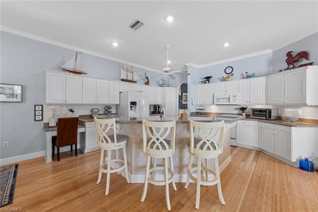 Kitchen featuring white appliances, visible vents, ornamental molding, ceiling fan, and white cabinets