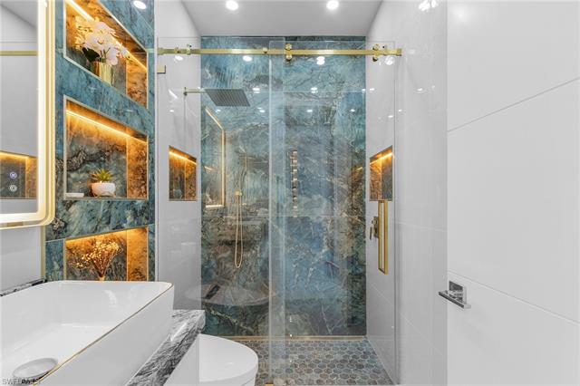 Full bathroom featuring tile walls, toilet, recessed lighting, and a marble finish shower