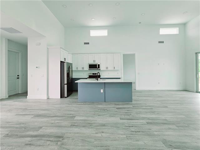 Kitchen featuring a high ceiling, open floor plan, a sink, and appliances with stainless steel finishes