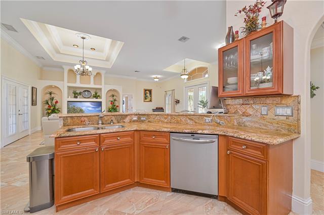 Kitchen w/ light stone counters, stainless steel appliances, open floor plan, and arched walkway