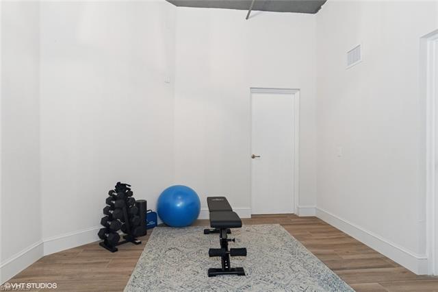 Exercise area featuring visible vents, baseboards, and wood finished floors