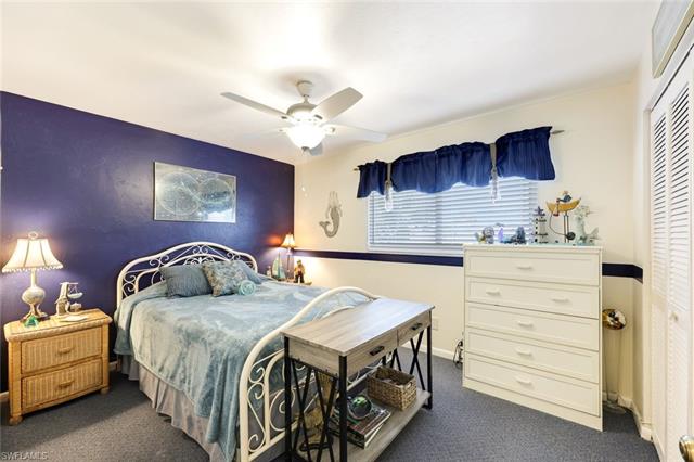 Bedroom with baseboards, ceiling fan, a closet, an accent wall, and dark colored carpet