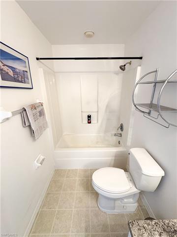 Bathroom with tile patterned flooring, toilet, bathtub / shower combination, and baseboards