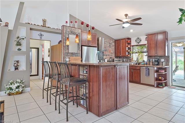 Kitchen featuring a ceiling fan, appliances with stainless steel finishes, lofted ceiling, open shelves, and light tile patterned floors