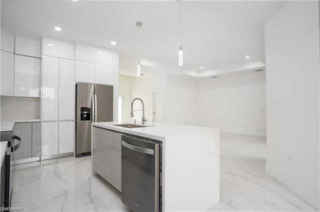 Kitchen with modern cabinets, a sink, marble finish floor, and appliances with stainless steel finishes