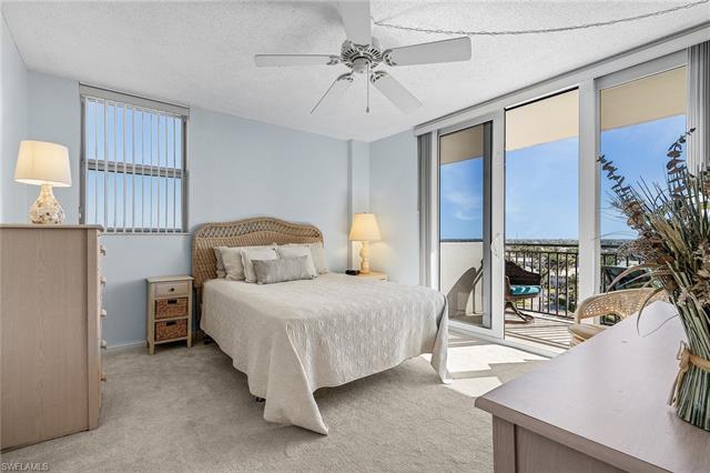 Bedroom with light carpet, access to exterior, expansive windows, and a textured ceiling