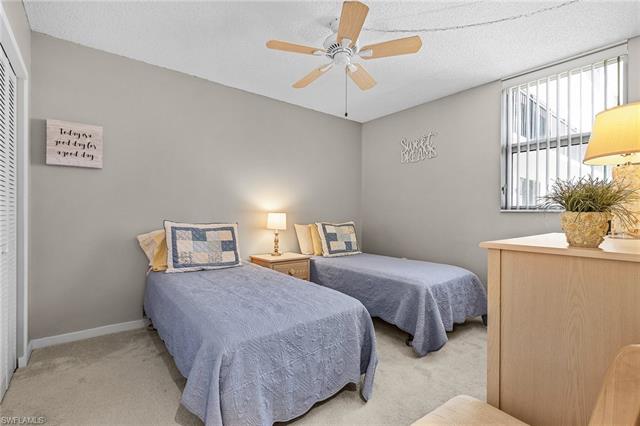 Bedroom with baseboards, a textured ceiling, ceiling fan, light carpet, and a closet