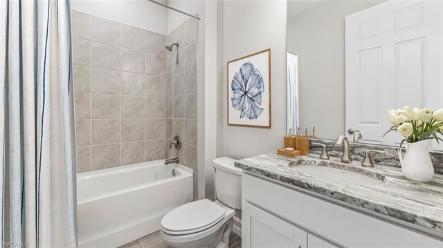 Bathroom with vanity, toilet, and shower / tub combo with curtain