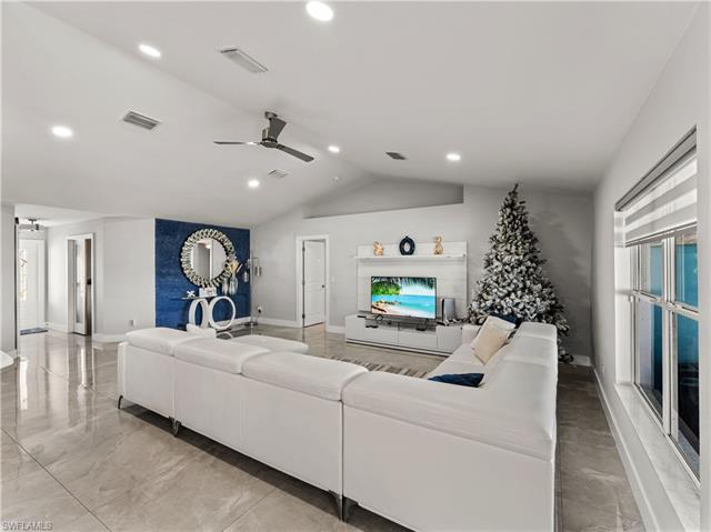 Living room with a ceiling fan, lofted ceiling, marble finish floor, visible vents, and recessed lighting