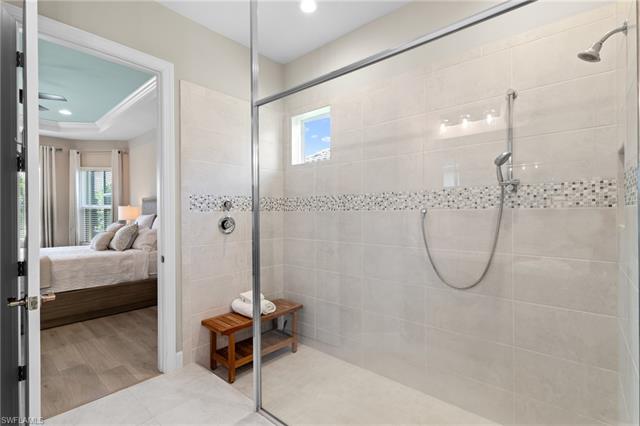 Ensuite bathroom with connected bathroom, wood finished floors, tiled shower, and recessed lighting