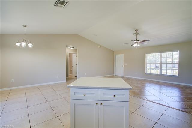 Kitchen featuring light tile patterned floors, visible vents, lofted ceiling, ceiling fan with notable chandelier, and open floor plan