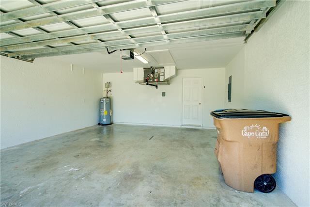Garage with electric panel, a garage door opener, and water heater