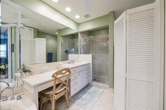 Bathroom featuring tile patterned flooring, vanity, a stall shower, visible vents, and a closet