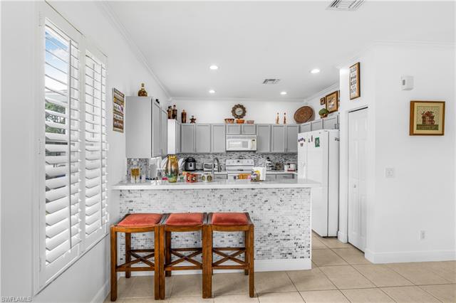 Kitchen featuring light countertops, crown molding, white appliances, gray cabinetry, and decorative backsplash