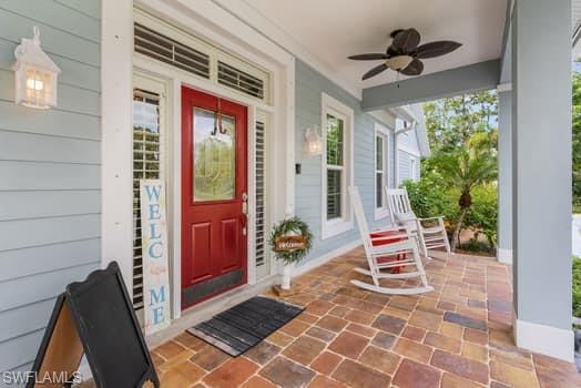 Doorway to property featuring covered porch and ceiling fan