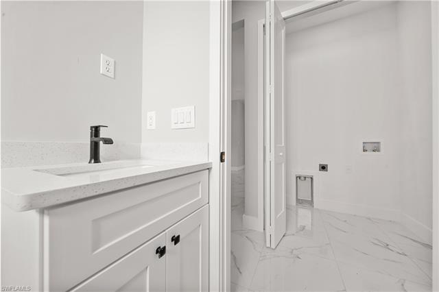 Bathroom with baseboards, marble finish floor, and vanity