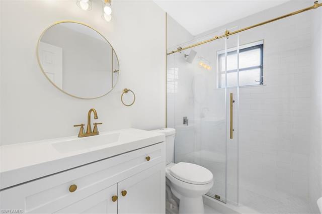 Bathroom featuring a shower stall, toilet, and vanity