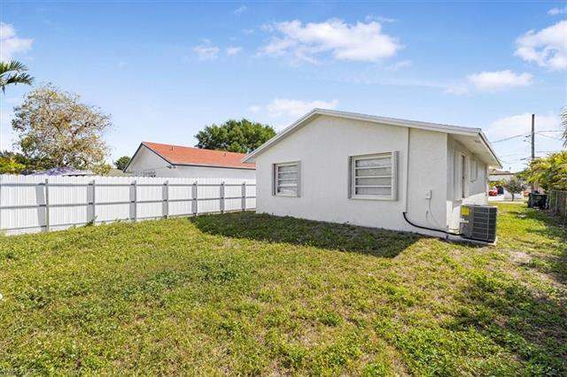 View of home's exterior featuring cooling unit, fence, stucco siding, and a yard
