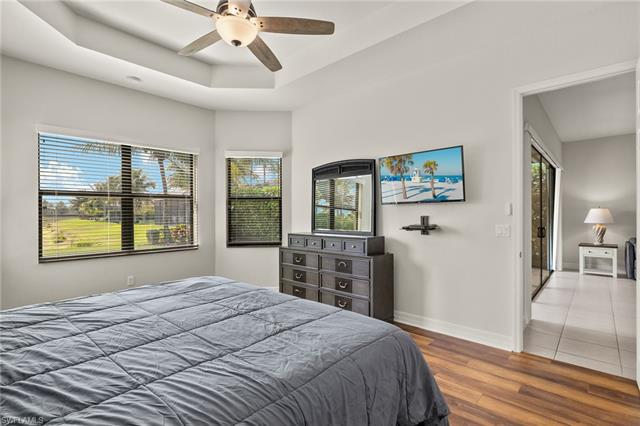 Bedroom featuring baseboards, a ceiling fan, wood finished floors, and a raised ceiling