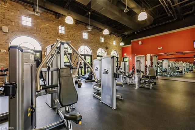 Exercise room featuring a towering ceiling and brick wall