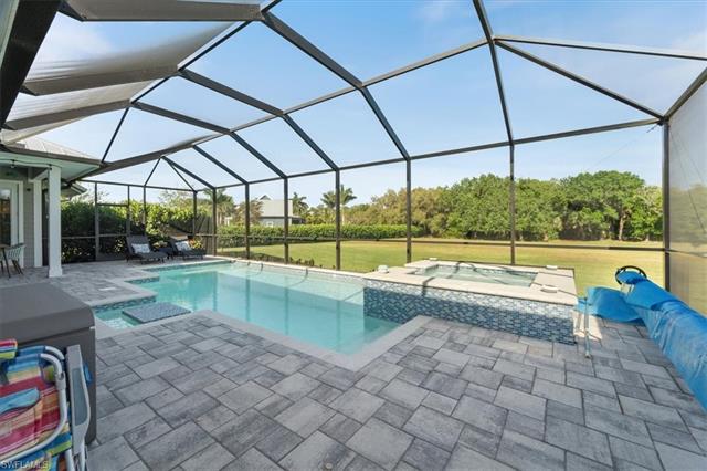 View of pool with a pool with connected hot tub, a lanai, a patio, and a yard