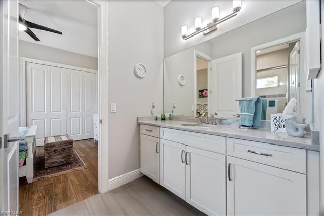 Bathroom with vanity, baseboards, wood finished floors, and a ceiling fan