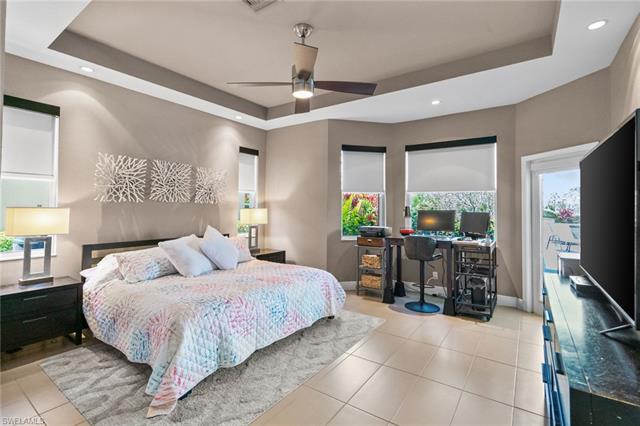Tiled bedroom featuring baseboards, a tray ceiling, recessed lighting, and a ceiling fan
