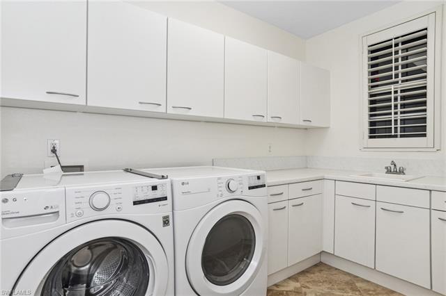 Washroom featuring washing machine and clothes dryer, a sink, and cabinet space